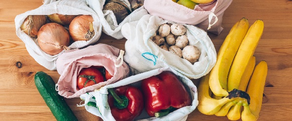 Fresh groceries in eco cotton bags on wooden table, flat lay. Zero Waste shopping concept. Vegetables from market in reusable bags. Ban single use plastic. Sustainable lifestyle